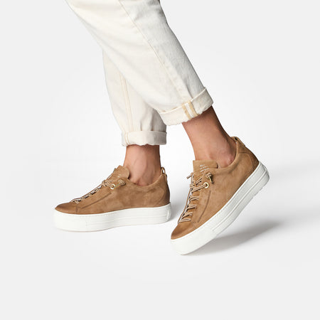 Women wearing brown Paul Green Faye sneakers with white soles paired with light-colored pants against a white background.
