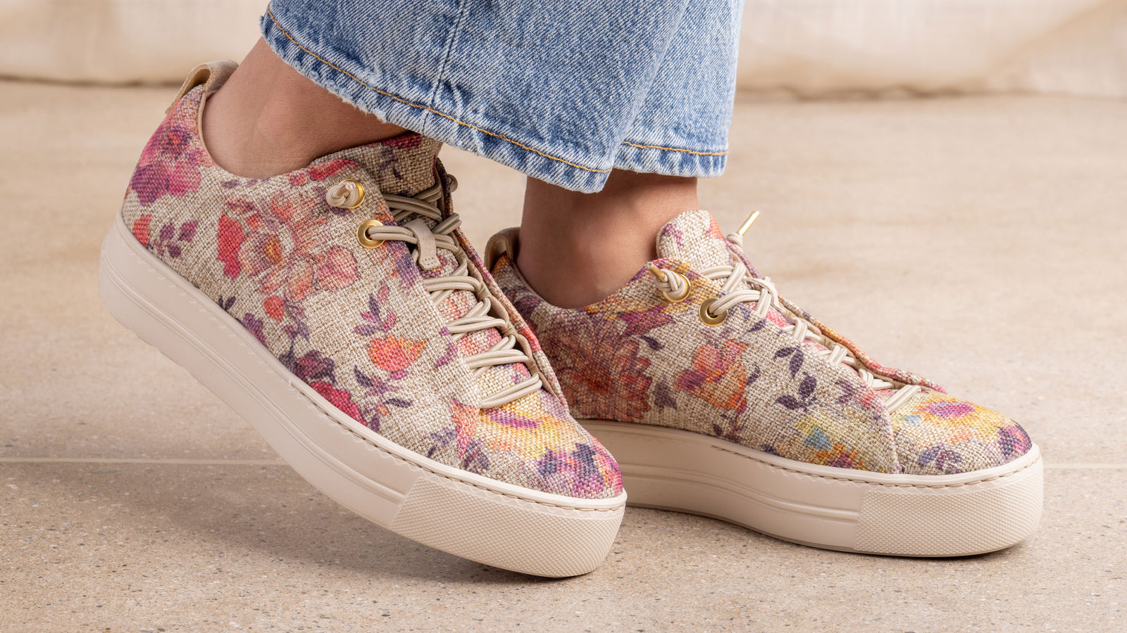 Floral Paul Green Desi sneakers worn with denim jeans on a neutral background.